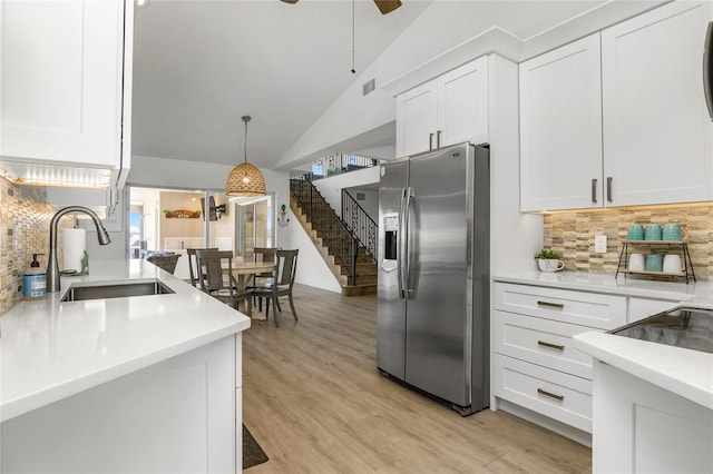 1109 SW 44th St, Cape Coral, FL 33914 - kitchen with stainless steel fridge, a sink, decorative backsplash, white cabinetry, and high vaulted ceiling