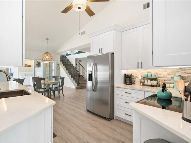 1109 SW 44th St, Cape Coral, FL 33914 - kitchen with stainless steel refrigerator with ice dispenser, a sink, white cabinetry, light countertops, and high vaulted ceiling