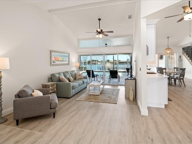 1109 SW 44th St, Cape Coral, FL 33914 - living room featuring a ceiling fan, light wood-style flooring, stairs, high vaulted ceiling, and baseboards