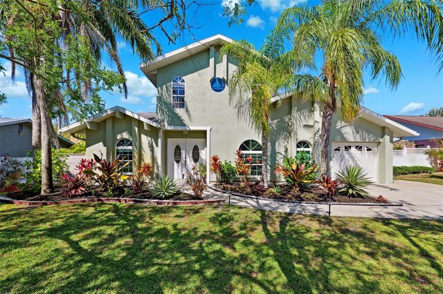 mediterranean / spanish-style home with a front yard, a garage, fence, concrete driveway, and stucco siding