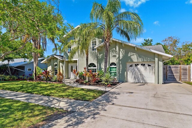 view of front facade with a garage, a front lawn, fence, stucco siding, and concrete driveway