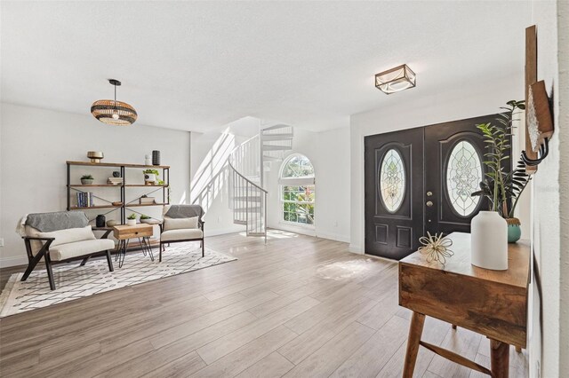 entrance foyer featuring baseboards, a textured ceiling, stairs, and wood finished floors