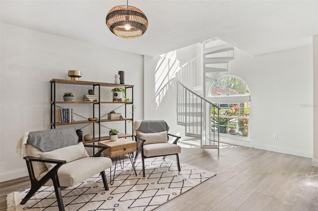 living area with stairs, baseboards, a chandelier, and wood finished floors