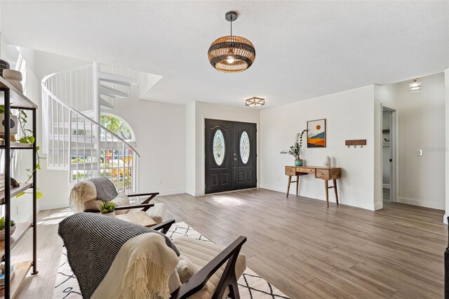 foyer featuring light wood-style floors, baseboards, and stairway