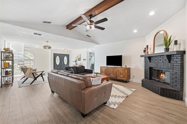 living room featuring ceiling fan, visible vents, lofted ceiling with beams, and wood finished floors