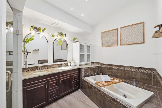 full bathroom featuring double vanity, visible vents, a sink, and a garden tub