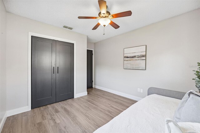 bedroom with light wood-style flooring, a ceiling fan, baseboards, visible vents, and a closet