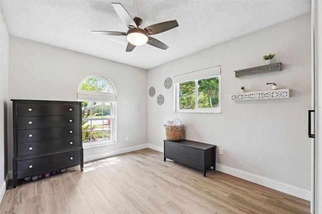 bedroom with baseboards, a ceiling fan, a textured ceiling, and wood finished floors
