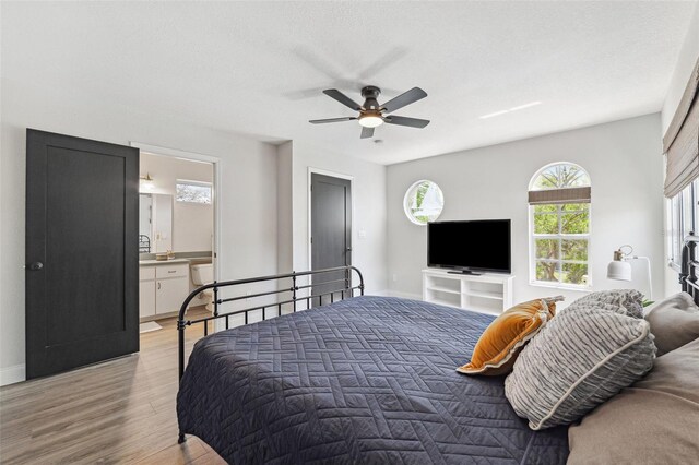 bedroom featuring ensuite bathroom, light wood-style flooring, ceiling fan, and baseboards