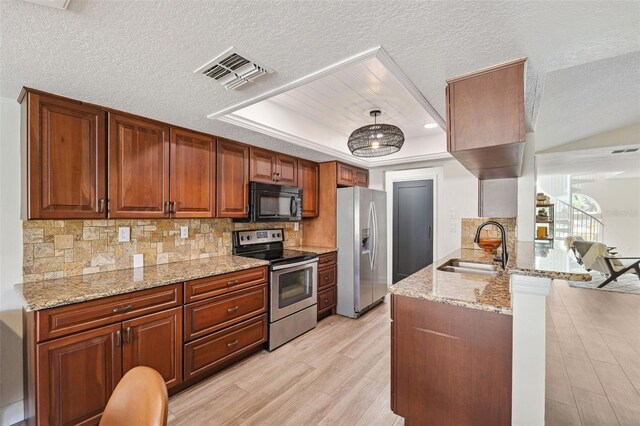 kitchen featuring visible vents, a peninsula, a sink, light wood finished floors, and appliances with stainless steel finishes