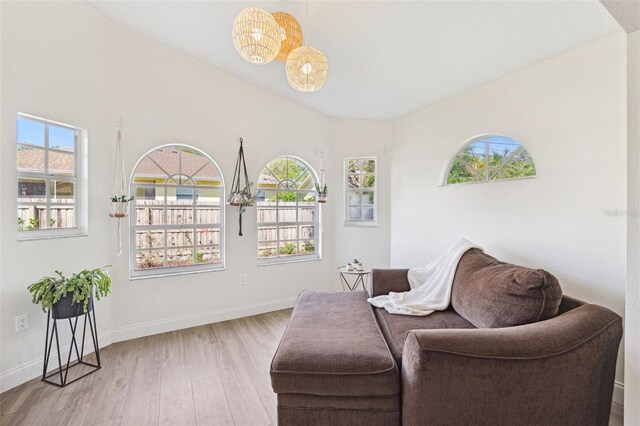 sitting room featuring a healthy amount of sunlight, baseboards, wood finished floors, and a chandelier