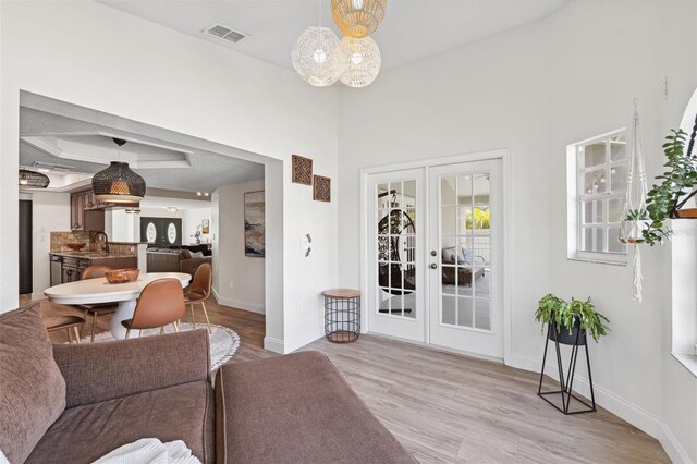 living area featuring baseboards, french doors, light wood-type flooring, and visible vents