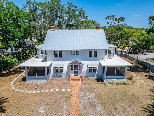 5603 Palmetto Rd, New Port Richey, FL 34652 - back of house with a chimney, a sunroom, metal roof, and a balcony