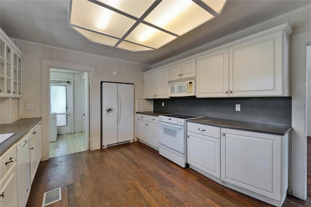 5603 Palmetto Rd, New Port Richey, FL 34652 - kitchen featuring crown molding, dark countertops, white appliances, dark wood-type flooring, and visible vents