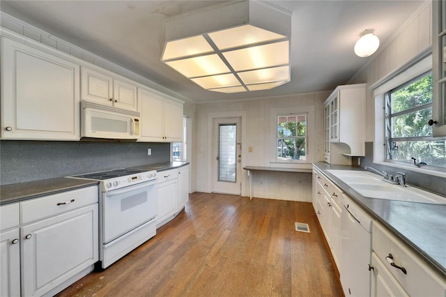 5603 Palmetto Rd, New Port Richey, FL 34652 - kitchen featuring dark countertops, a sink, white appliances, white cabinetry, and wood finished floors
