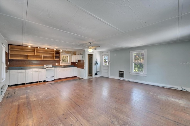 5603 Palmetto Rd, New Port Richey, FL 34652 - unfurnished living room with wood-type flooring, heating unit, baseboards, ceiling fan, and a sink
