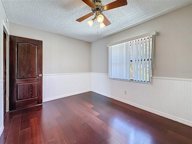 705 Cypress St, Tarpon Springs, FL 34689 - unfurnished room featuring a textured ceiling, dark wood-style flooring, a ceiling fan, and a wainscoted wall