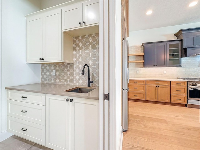 kitchen with light countertops, decorative backsplash, a sink, and stainless steel stove