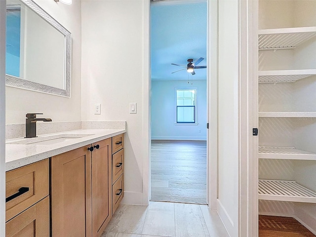 bathroom featuring vanity, a ceiling fan, baseboards, and wood finished floors
