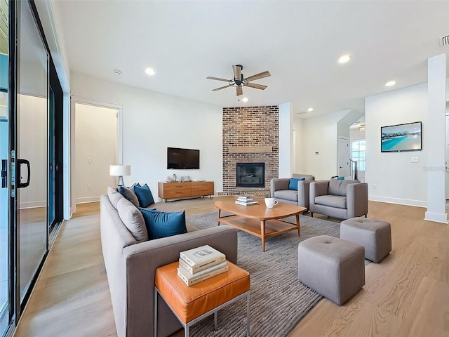 living area featuring a brick fireplace, a ceiling fan, recessed lighting, and light wood-type flooring