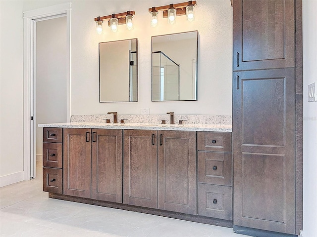full bath with a sink, a shower with door, and double vanity