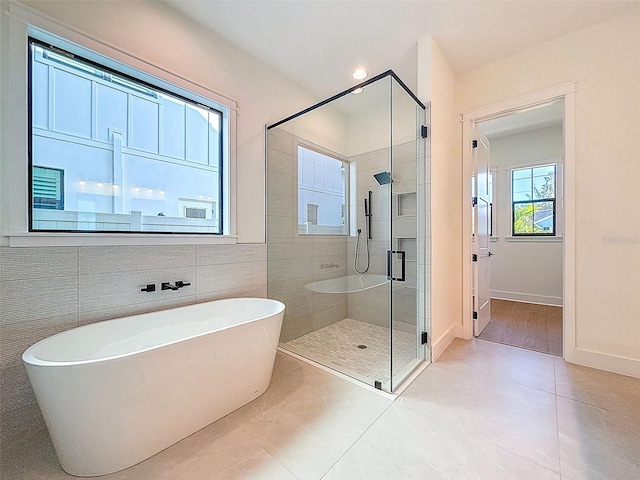 bathroom featuring baseboards, tile patterned floors, a stall shower, and a soaking tub