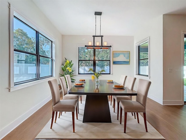 dining area with baseboards, wood finished floors, and a notable chandelier