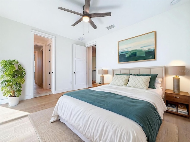 bedroom featuring baseboards, a ceiling fan, light wood-style flooring, and visible vents
