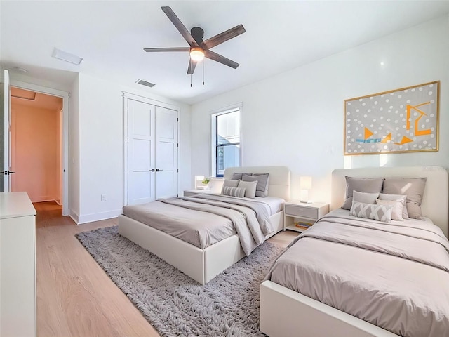 bedroom featuring visible vents, a closet, baseboards, a ceiling fan, and light wood-style flooring