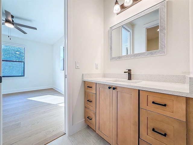 bathroom with wood finished floors, baseboards, ceiling fan, and vanity