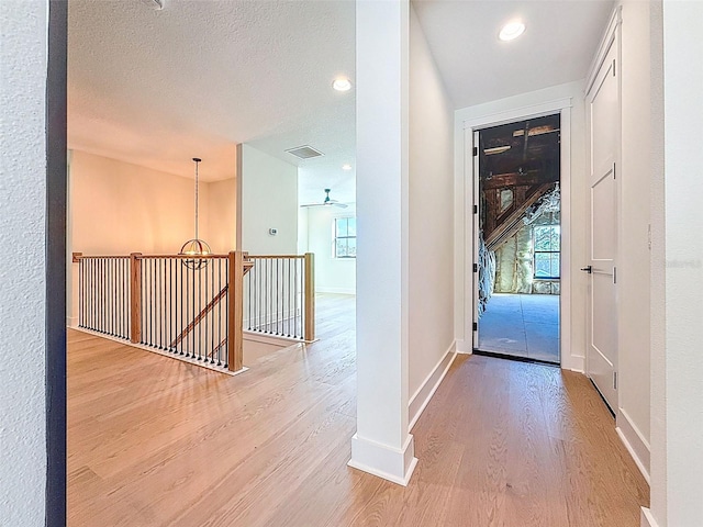 hall with recessed lighting, baseboards, an upstairs landing, and wood finished floors