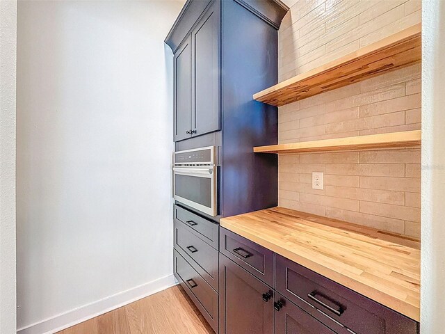 kitchen with backsplash, open shelves, baseboards, butcher block counters, and oven