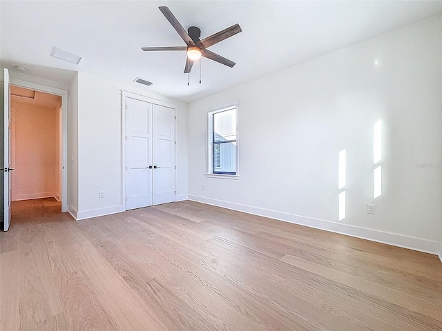 unfurnished bedroom with baseboards, a closet, wood finished floors, and visible vents