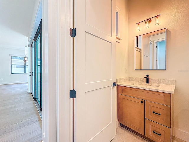 corridor with baseboards, a sink, and light wood-style flooring