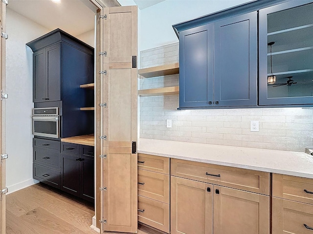 kitchen with light wood-type flooring, open shelves, tasteful backsplash, and light countertops