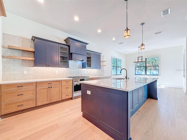 kitchen with a sink, open shelves, light wood-style flooring, and stainless steel stove