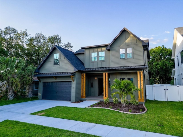 view of front of home featuring board and batten siding, driveway, a standing seam roof, a front yard, and a gate