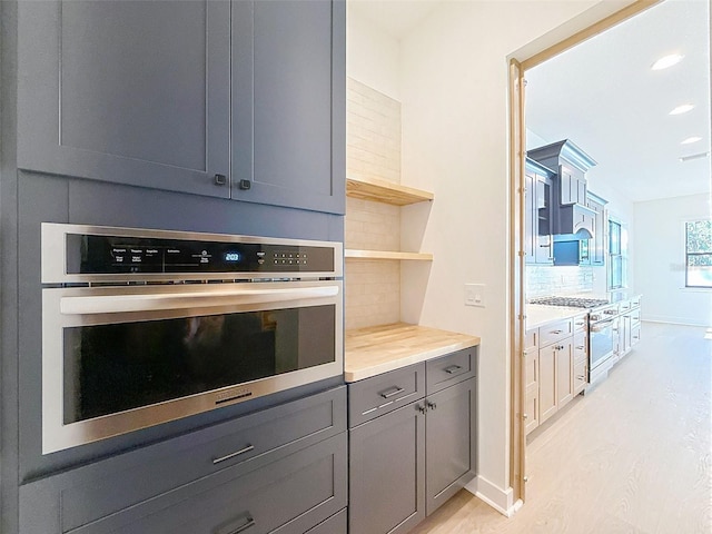 kitchen featuring gray cabinetry, appliances with stainless steel finishes, tasteful backsplash, and light wood-type flooring