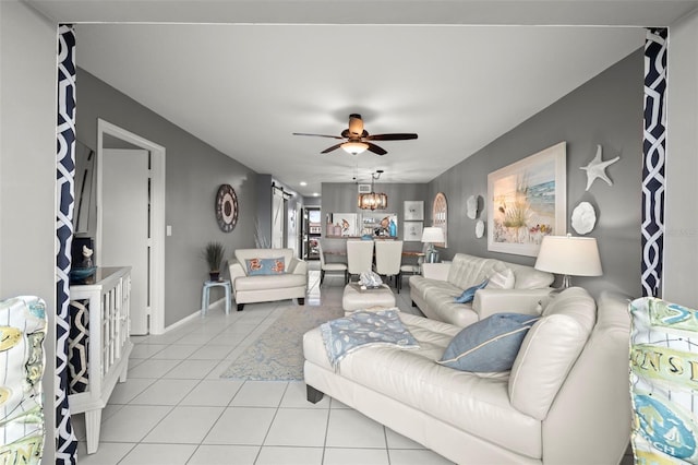 living room with baseboards, ceiling fan with notable chandelier, and light tile patterned floors