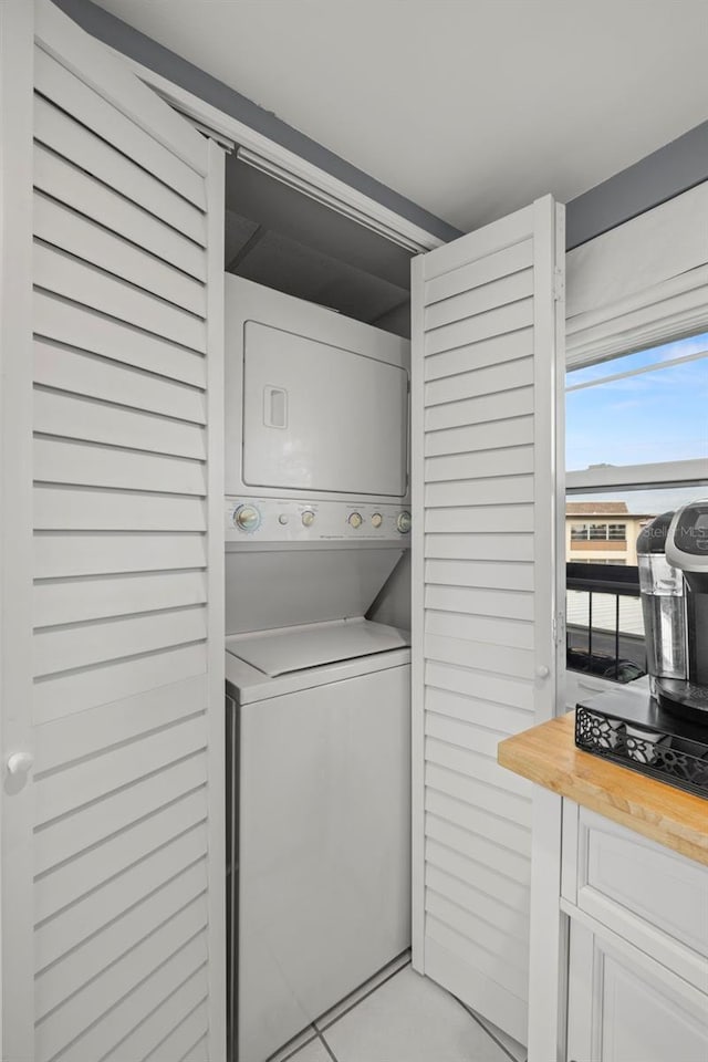 laundry room with light tile patterned floors, laundry area, and stacked washer and dryer