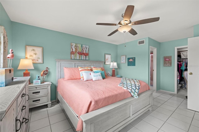 bedroom featuring a walk in closet, ceiling fan, visible vents, light tile patterned floors, and baseboards