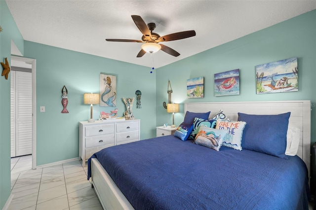 bedroom with a ceiling fan, a textured ceiling, and marble finish floor