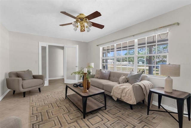 living area featuring light tile patterned floors, baseboards, and a ceiling fan