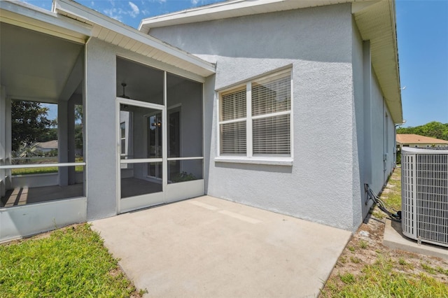 11220 Godwit Ct, New Port Richey, FL 34654 - back of house with central AC, a sunroom, stucco siding, and a patio