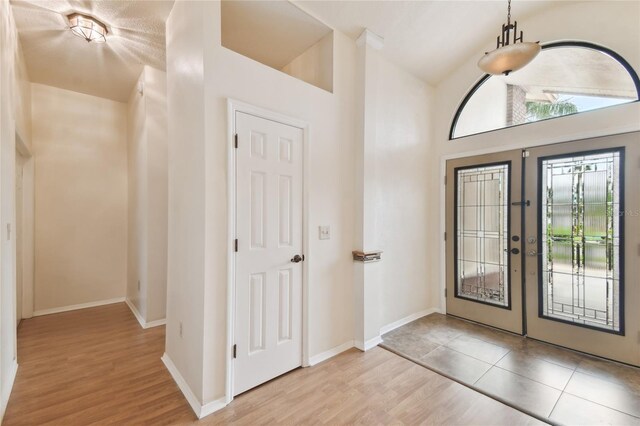 1831 Stable Trl, Palm Harbor, FL 34685 - entrance foyer featuring french doors, light wood-style flooring, baseboards, and high vaulted ceiling