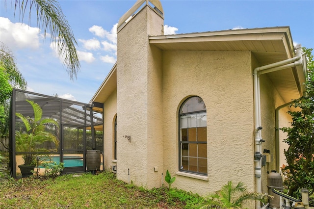 1831 Stable Trl, Palm Harbor, FL 34685 - view of side of property with glass enclosure, an outdoor pool, stucco siding, and a chimney