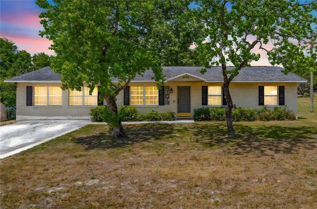 ranch-style house featuring brick siding, a shingled roof, and a front lawn