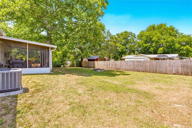 view of yard with a sunroom, a fenced backyard, and central air condition unit