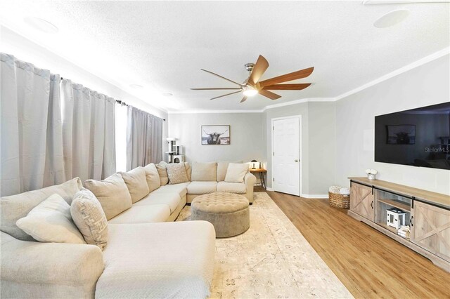 living room with a ceiling fan, baseboards, ornamental molding, and light wood-style flooring