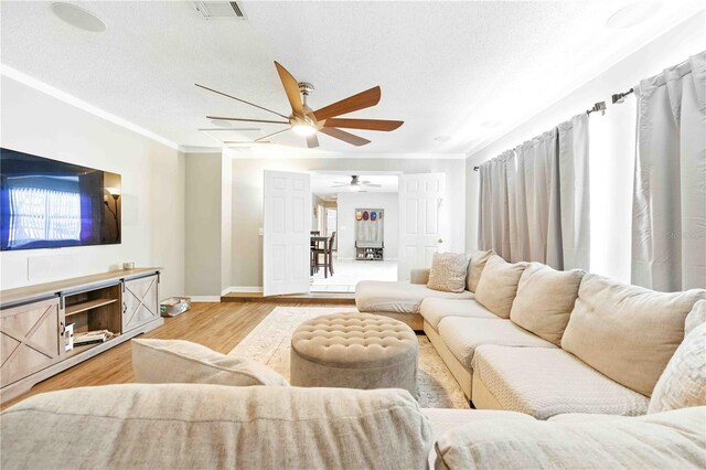 living area with ceiling fan, visible vents, ornamental molding, and light wood-style floors